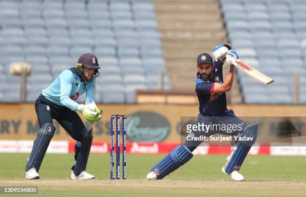 England wicketkeeper Jos Buttler looks on as India batsman Virat Kohli cuts a ball for some runs during the 2nd One Day International between India...