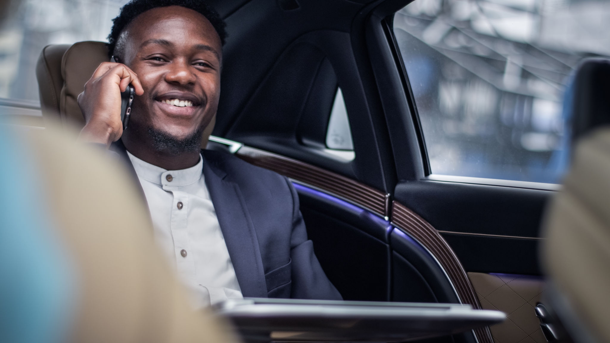 African businessman in taxi, working on the back seat. Making business call African businessman in taxi, working on the back seat. Making business call