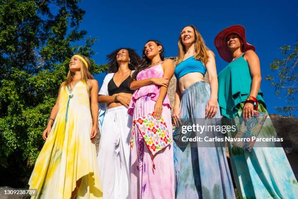 group of women posing in coloured dresses in a garden of a resort - pasarela moda stock-fotos und bilder