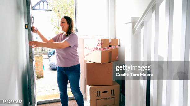 woman entering new house with boxes - key entering lock stock pictures, royalty-free photos & images
