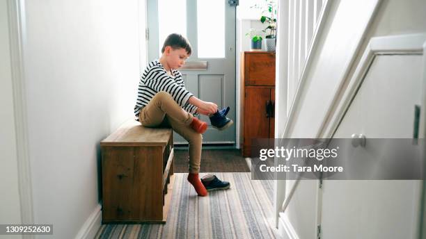 young boy putting on shoes - child getting dressed stock-fotos und bilder