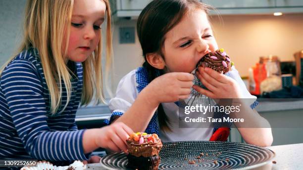 two girls eating cupcakes - cupcakes girls fotografías e imágenes de stock