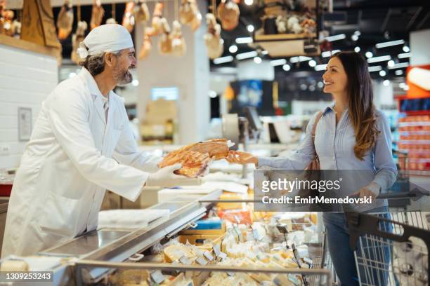 female customer choosing meat from deli counter in supermarket - baloney stock pictures, royalty-free photos & images