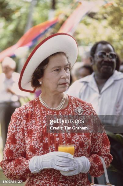 British Royal Queen Elizabeth II, wearing a red-and-white outfit and a white straw hat with red trim, in Honiara, Solomon Islands, 18th October 1982....