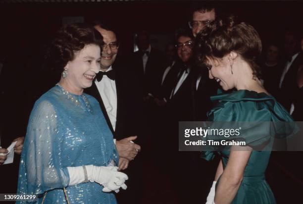 British Royal Queen Elizabeth II, wearing a blue outfit with white evening gloves, speaks with American actress Sally Field meets at the premiere of...