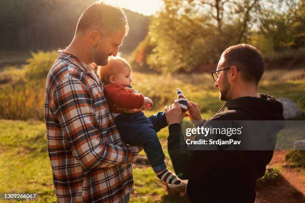 pareja gay amorosa con su bebé - persona gay fotografías e imágenes de stock