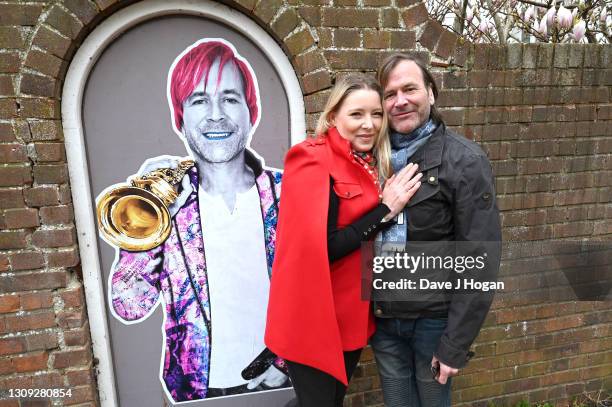 Steve Norman and Sabrina Winter stand alongside a commissioned art piece by "Postman Art" street artists on March 26, 2021 in Brighton, England. The...