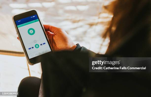 hand holding a smart phone which displays a media player app - upload stock-fotos und bilder