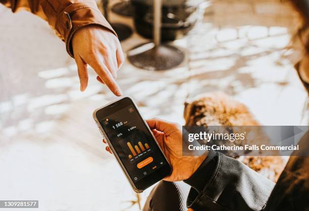 hand holding a smart phone displaying a fitness app - podomètre photos et images de collection