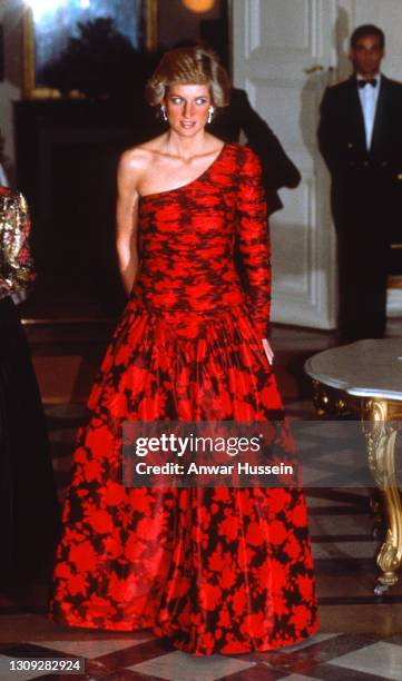 Diana, Princess of Wales, wearing a one-shouldered black and red evening gown designed by Catherine Walker, attends a dinner hosted by the British...