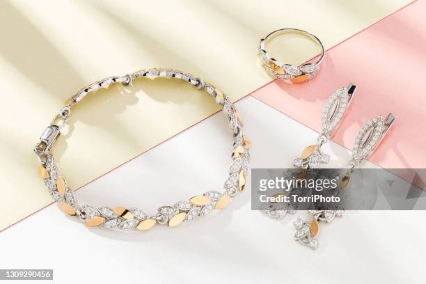 silver and gold set of jewelry in leaves shape decorated with diamonds. bracelet, earrings and ring - jewelry necklace stock-fotos und bilder