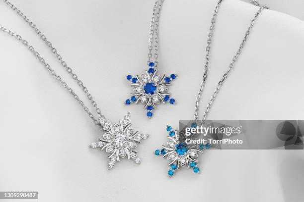 three silver snowflake shaped necklace charms on white background - diamond necklace stock pictures, royalty-free photos & images