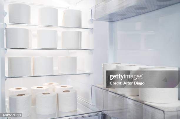 open refrigerator with large amount of toilet paper rolls inside. humorous storage concept. - open fridge stock-fotos und bilder