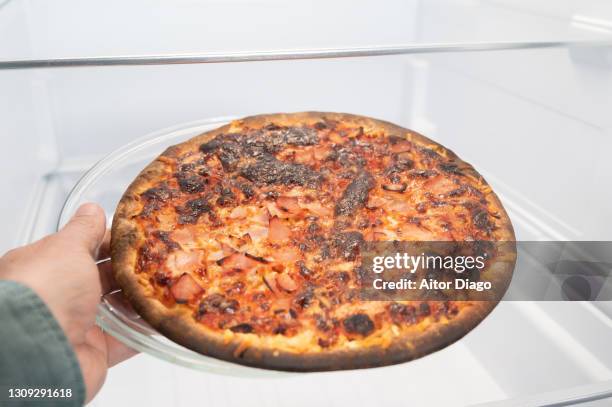 unrecognizable person (man) is going to take a pizza from the refrigerator. - burnt dinner stock pictures, royalty-free photos & images