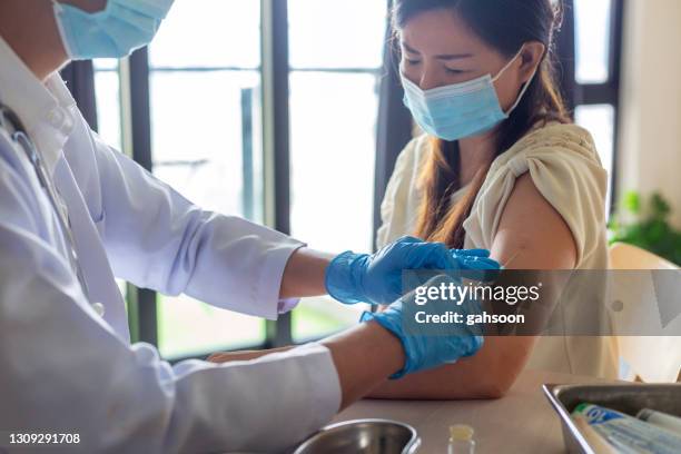 woman with face mask getting vaccinated, coronavirus concept - singapore hospital stock pictures, royalty-free photos & images