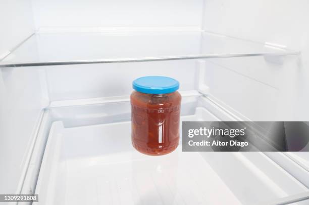 clear glass jar of crushed tomatoes inside a refrigerator. - kühlschrank leer stock-fotos und bilder