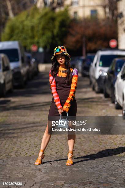 Alessandra Huynh @atiashuynh wears a fluffy colorful bob hat from Asos, a tie and dye multicolor top from Asos with printed patterns, a brown short...