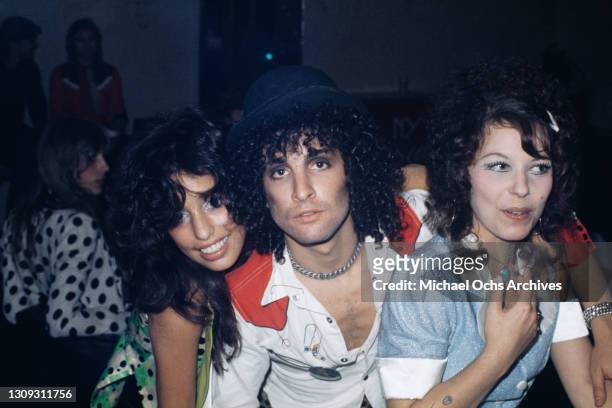 American groupie Lori Mattix , American guitarist Sylvain Sylvain , with permed hair wearing a bowler hat and a white shirt with red detail on the...