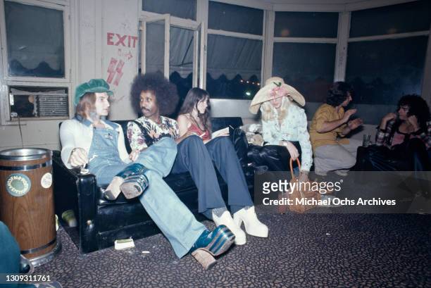 Clubbers sitting on a sofa backstage at the Whisky a Go Go, a nightclub on Sunset Boulevard in West Hollywood, California, circa 1975. On the wall...