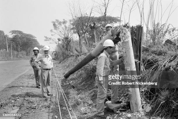 Portrait of workmen from a Salvadoran electric power company as they examine a damaged utility pole, Chalatenango department, El Salvador, May 4,...