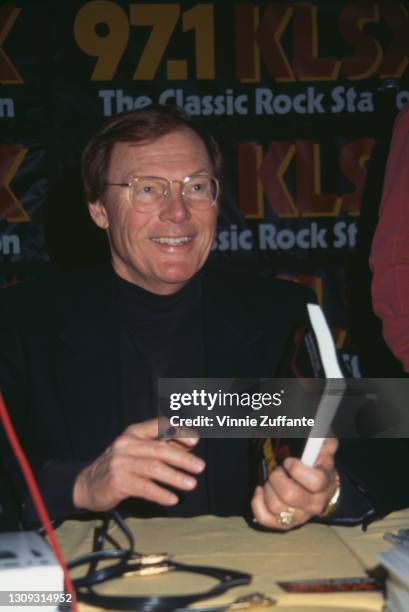 American actor Adam West signing copies of 'Back to the Batcave', a memoir of his time on the 'Batman' television series, at an unspecified location,...