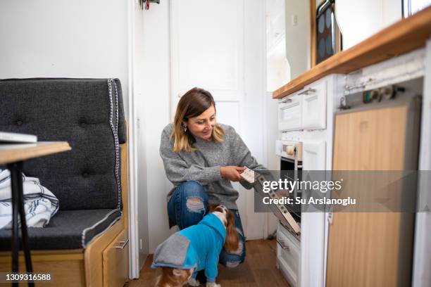 femme adulte utilisant le four dans sa caravane - mobile home photos et images de collection