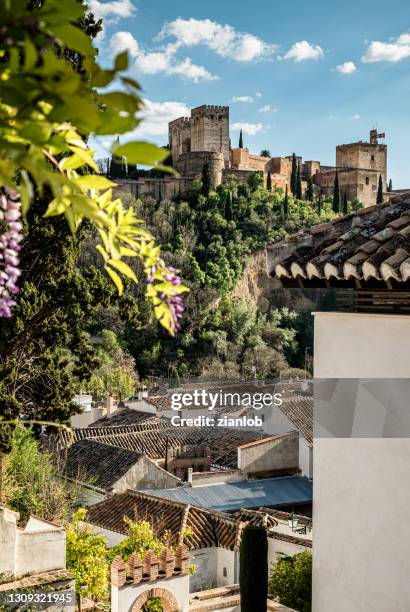 view of the alhambra between houses in the albaicín neighborhood. - granada españa stock pictures, royalty-free photos & images