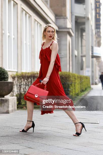 German model and actress Victoria Jancke wearing a red midi length dess by Longchamp, a red bag by Picard, black sandals by Aldo Shoes, sunglasses by...