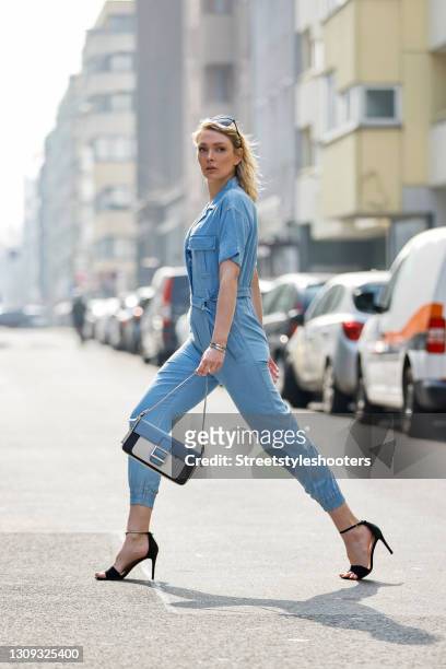 German model and actress Victoria Jancke wearing a light blue denim jeans jumpsuit by Guess, a blue and white bag by Picard, sunglasses by Prada, a...