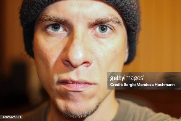 portrait of a man looking straight at the camera with a beanie and goatee - groene ogen stockfoto's en -beelden