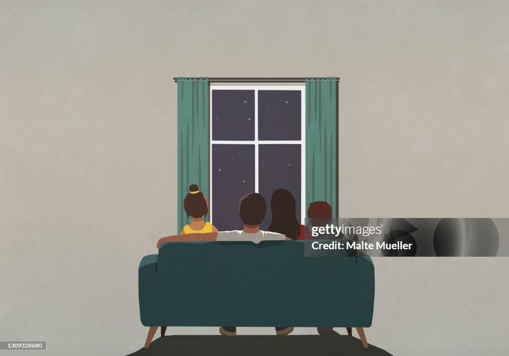 Family on sofa looking out window at starry night sky