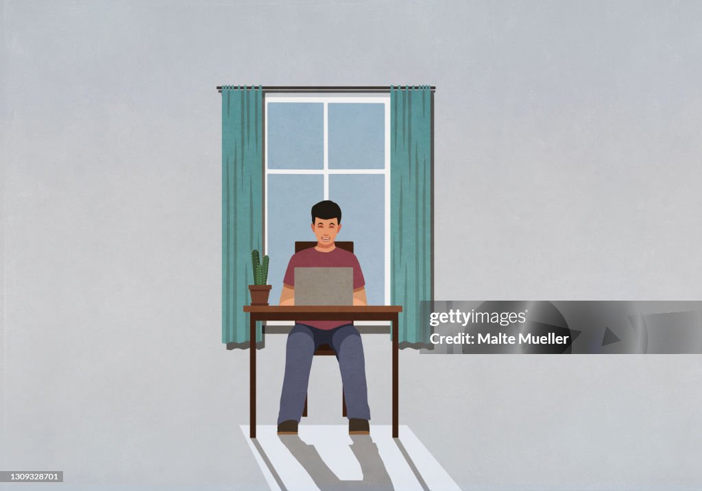 Man working from home at laptop in window