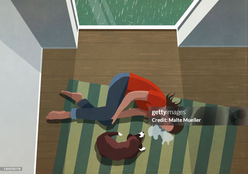 Dog laying next to depressed woman crying on floor