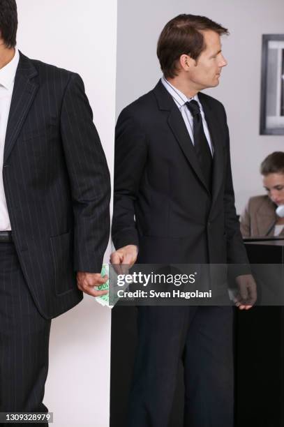 businessmen exchanging money secretly in office - data privacy foto e immagini stock