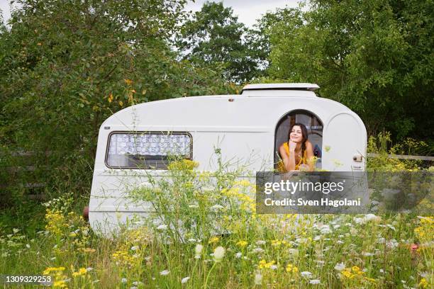 young woman relaxing inside camper trailer in idyllic meadow - camper trailer stock pictures, royalty-free photos & images