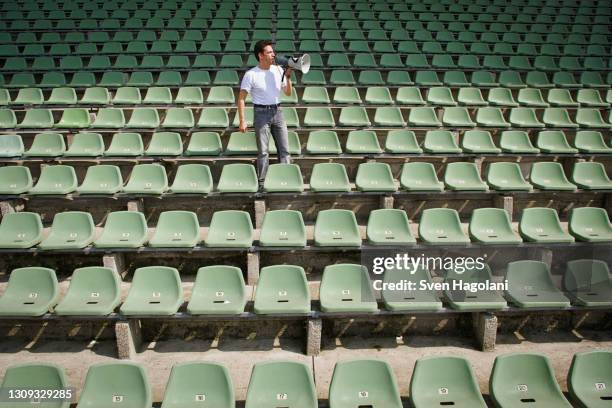 man with bullhorn in stadium with green seats - fans in the front row stock pictures, royalty-free photos & images