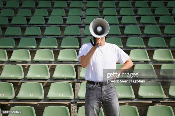 man using bullhorn among green stadium seats - leadership in coaching stock-fotos und bilder