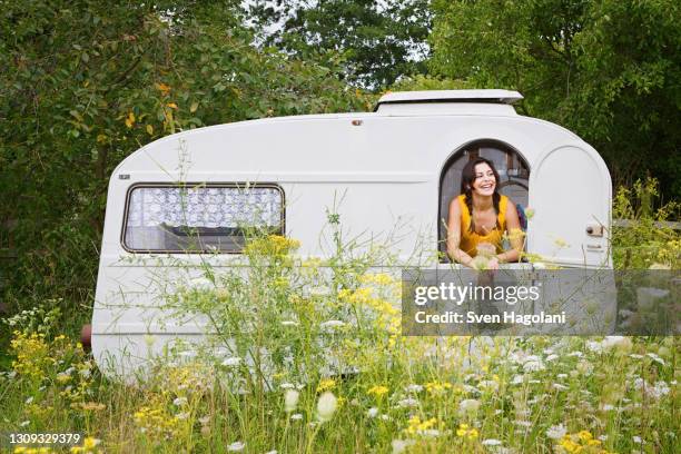 happy young woman in camper trail in meadow - sven hagolani stock-fotos und bilder