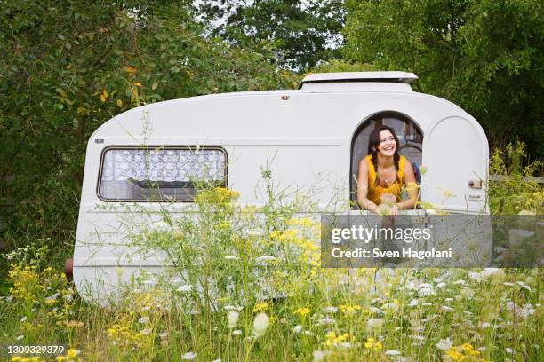 happy young woman in camper trail in meadow - sven hagolani stock pictures, royalty-free photos & images