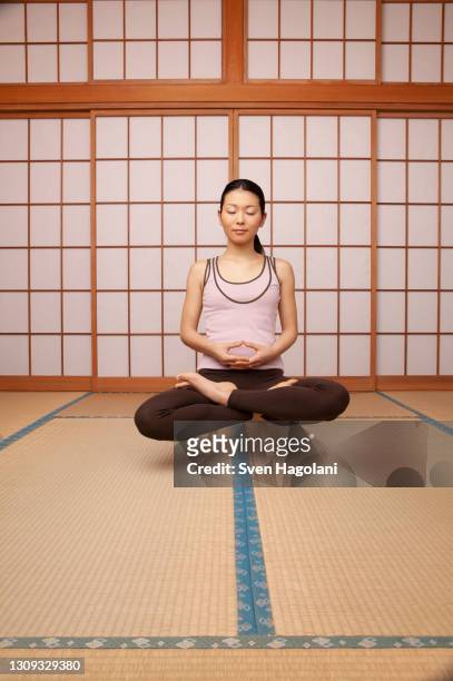 serene young woman meditating in lotus pose on stool - sven hagolani stock-fotos und bilder