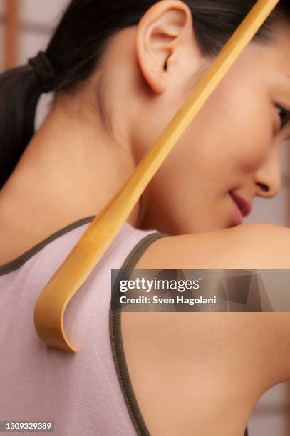 close up young woman using wooden back scratcher - sven hagolani stock pictures, royalty-free photos & images