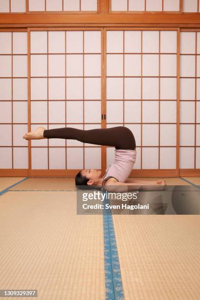 young woman practicing yoga pose on mat - sven hagolani stock pictures, royalty-free photos & images