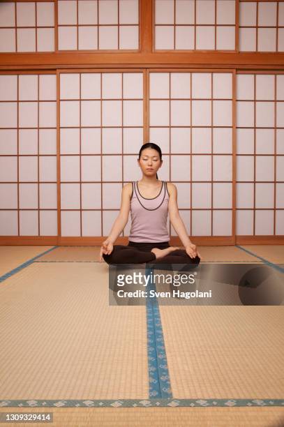 serene young woman meditating in lotus pose on mat - sven hagolani stock pictures, royalty-free photos & images