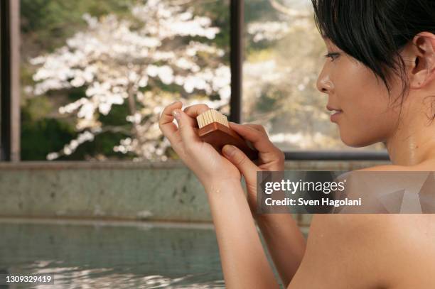 young woman using nail brush in pool at onsen - sven hagolani stock pictures, royalty-free photos & images