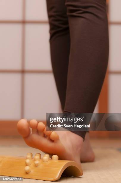 close up young barefoot woman using foot massager in spa - sven hagolani stock-fotos und bilder