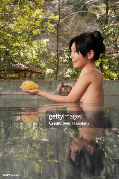 beautiful young woman with loofah in hot spring water at onsen - sven hagolani stock-fotos und bilder