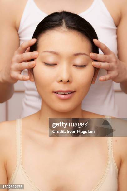 serene young woman receiving scalp massage at spa - sven hagolani stock-fotos und bilder