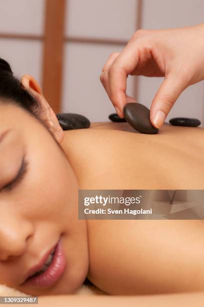 close up young woman receiving hot stone massage - sven hagolani stock pictures, royalty-free photos & images