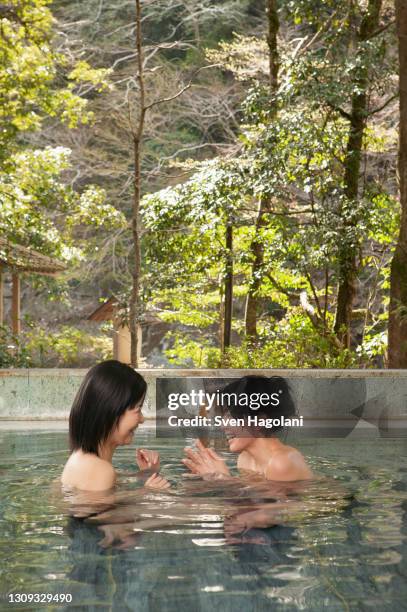 happy young women friends soaking in water at onsen spa - sven hagolani stock-fotos und bilder