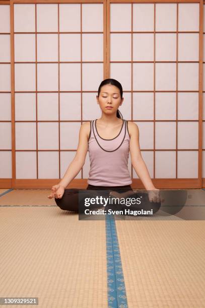 serene young woman meditating in lotus pose on mat - sven hagolani stock pictures, royalty-free photos & images